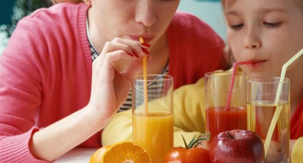 Портрет крупным планом мать и дочь пьют томатный и апельсиновый сок и смотрят в камеру — стоковое видео