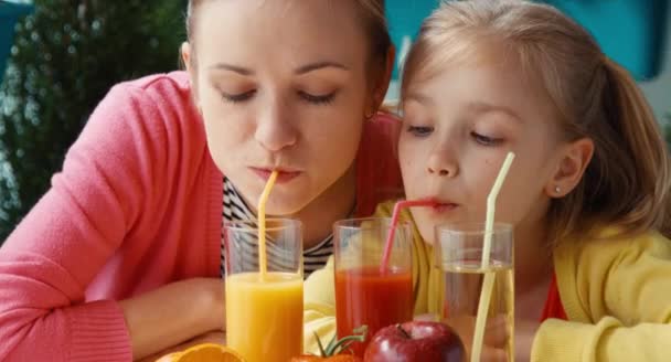 Mãe e filha bebendo tomate e suco de laranja e olhando para a câmera — Vídeo de Stock