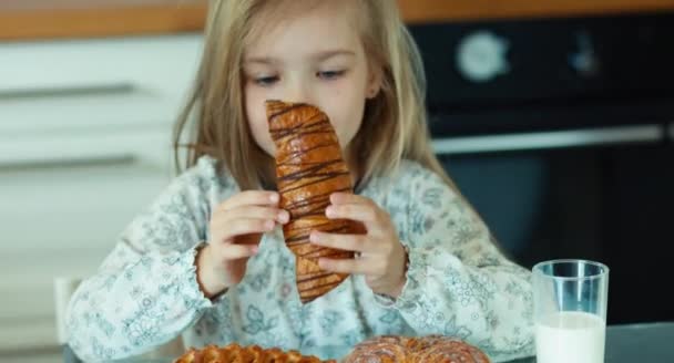 Nahaufnahme Porträt Kind isst Brötchen in der Küche und blickt in die Kamera — Stockvideo