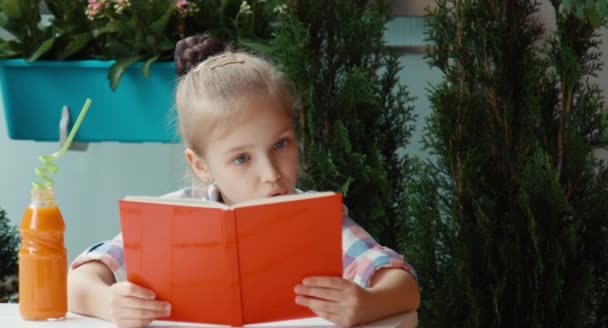 Retrato chica leyendo un libro y sonriendo a la cámara — Vídeos de Stock