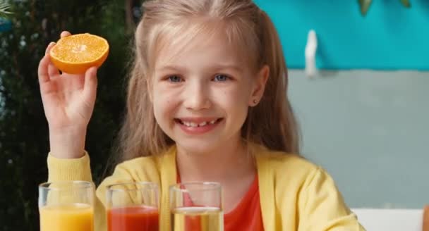 Усміхнена дівчина тримає апельсин і посміхається на камеру. Палець вгору. гаразд — стокове відео