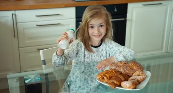 Bambino fa colazione, la ragazza apre una bottiglia di yogurt. Ragazza che beve yogurt. Guardando la telecamera. Pollice in alto. Va bene. — Video Stock