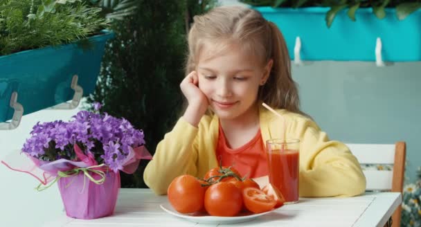 Дівчина захоплюється красивими помідорами. Дитина збирається з'їсти їх. Сміється з камери. Великі пальці вгору. гаразд — стокове відео