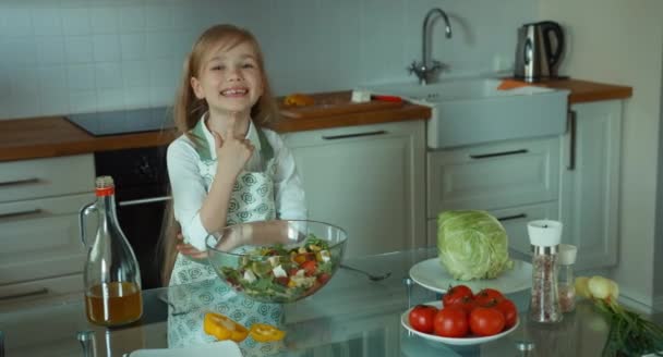 Детский повар приготовил салат. Девушка предлагает зрителю миску салата — стоковое видео