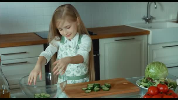 Menina colocando pepino fatiado em uma tigela. Zumbido — Vídeo de Stock