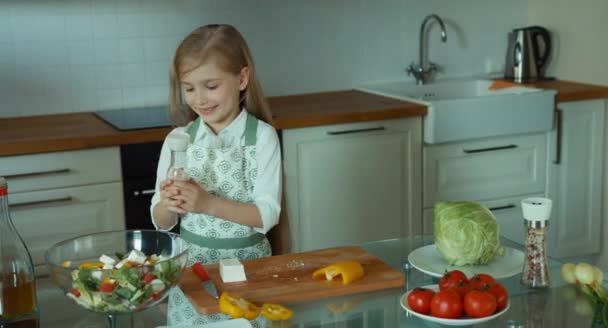 Mädchensalat streut Salz. Kinderkoch in der Küche — Stockvideo