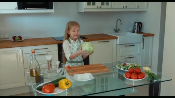 Дівчина-кухар на кухні тримає капусту і дивиться на камеру і сміється. Палець вгору. Добре. Збільшення — стокове відео