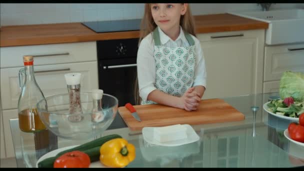 Menina chef na cozinha olhando para a câmera e sorrindo. Polegares para cima. Muito bem, Panning. Zumbido — Vídeo de Stock