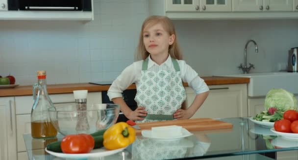 Fille souriante Chef dans la cuisine regardant la caméra. Enfant tenant la main sur la ceinture. Levez le pouce. D'accord. — Video