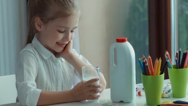 Preschooler girl drinking milk. Looking at window and camera and smiling. Zooming — Stock Video