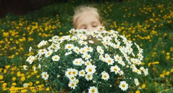 Vértes portré gyermek, és a nagy csokor fehér virágot. Gyerek nézi a kamerát, és mosolyogva — Stock videók