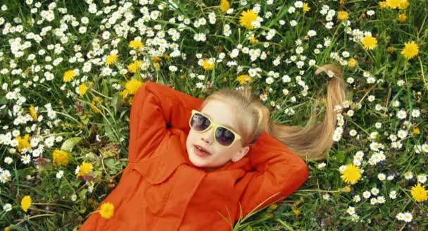 Primer plano retrato preescolar chica acostada en la hierba y mirando a la cámara — Vídeos de Stock