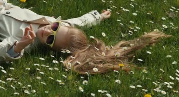 Vacker flicka liggande i fält av blommor och leende. Tittar på blomman. Våra kläder barn krypande fruktansvärda spindel — Stockvideo