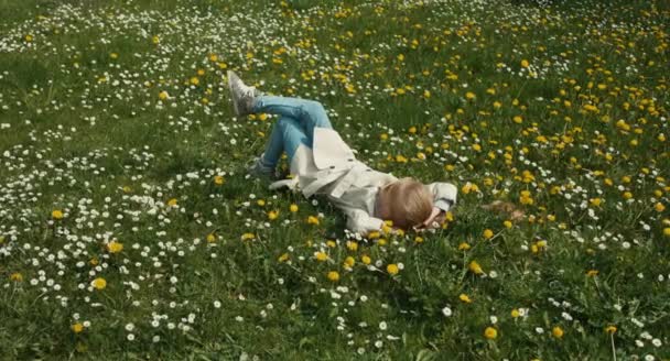 Météo printanière. Enfant couché sur l'herbe et ne fait rien. Fille étirer soi-même — Video