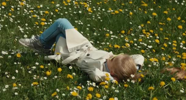 Tempo primaverile. Bambino si trova sull'erba e non fa nulla. Allungati. — Video Stock