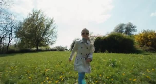 Vrolijk meisje draait op het gras in het park — Stockvideo