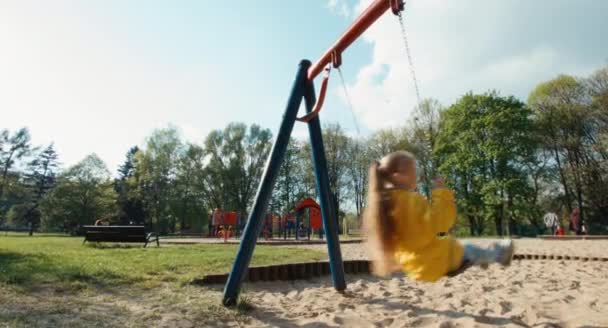 Niña en edad preescolar cabalgando en un columpio en el parque — Vídeos de Stock