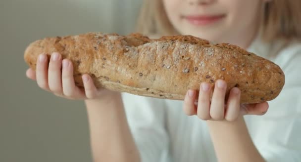 Menina cheirando um pão e olhando para a câmera — Vídeo de Stock