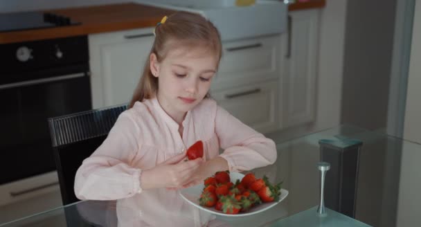 Child eating a big red strawberry and looking at camera. Top view — Stock Video