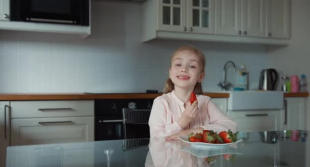 Pulgar hacia arriba. Un niño comiendo una fresa roja grande y mirando a la cámara. Panorama — Vídeo de stock