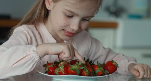 Primer plano retrato niña y un gran plato de fresas. Chica contando fresas — Vídeos de Stock