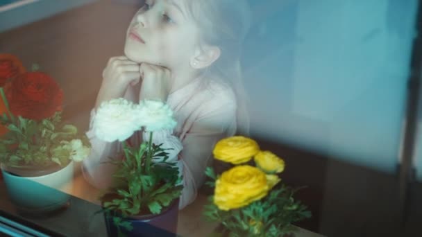 Flower girl looking out the window and smiling. Filming through the window — Stock Video