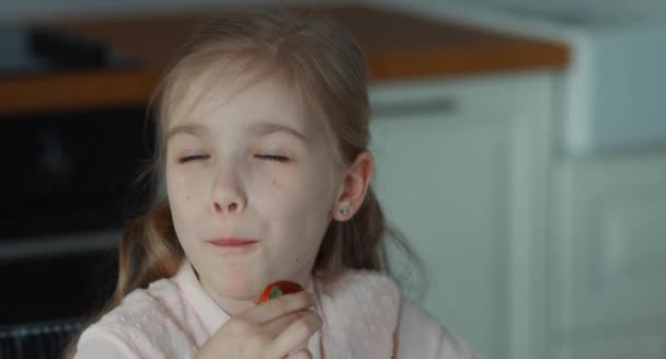 Closeup portrait girl eating a big red strawberry and looking at camera — Stock Video