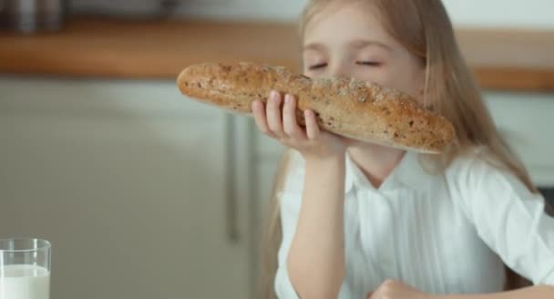 Chica oliendo un pan y riendo. Pulgar hacia arriba. Ok. — Vídeos de Stock