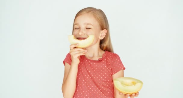 Dívka čichání žluté melouny na bílém pozadí. Dítě zobrazeno meloun na kameru — Stock video