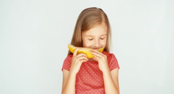 Menina comendo melão amarelo no fundo branco. Melão muito saboroso. Polegar para cima. Está bem. — Vídeo de Stock