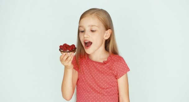 Chica comiendo un pastel con frambuesas en el fondo blanco — Vídeos de Stock