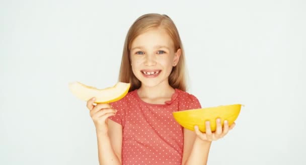 Girl holding yellow melon on the white background and laughing at camera. Child showing melon at camera — Stock Video