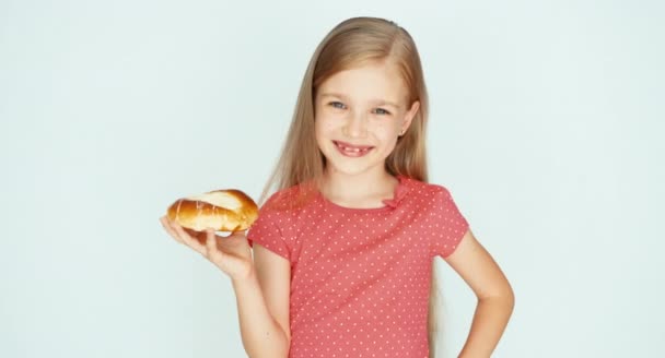 Mädchen hält einen Kuchen mit Käse in der Hand und schnuppert daran. Kind reibt sich den Bauch. Kind auf weißem Hintergrund — Stockvideo
