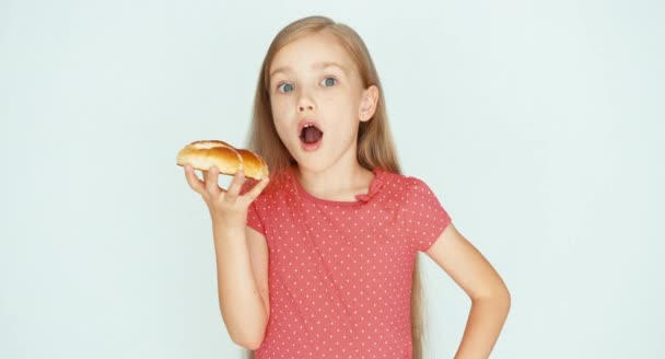 Une fille tenant un gâteau au fromage. L'enfant se frotte le ventre. Enfant sur fond blanc — Video