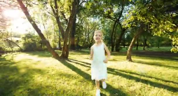 Mädchen läuft in der Sonne durch den Park — Stockvideo