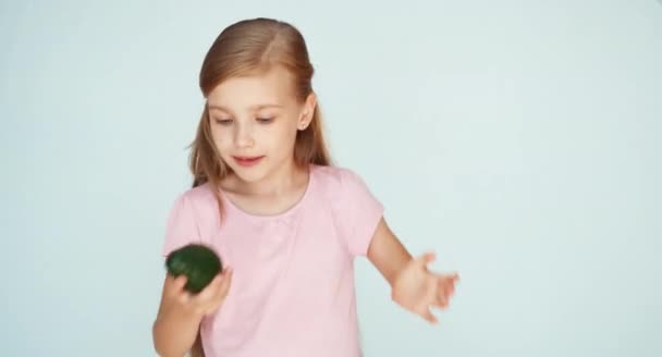 Chica jugando con aguacate y riendo de la cámara en el fondo blanco — Vídeos de Stock