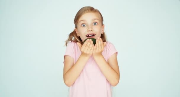Mädchen schnüffelt Avocado und hält sie in der Handfläche und zeigt sie vor der Kamera auf weißem Hintergrund — Stockvideo