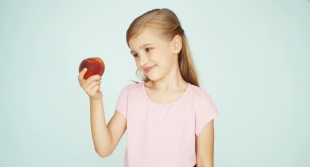 Девушка ест персик и целует его на белом фоне — стоковое видео