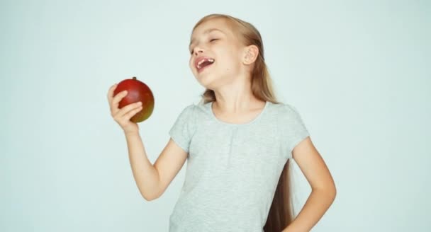 Chica oliendo un mango y riéndose de la cámara. Niño con fruta sobre fondo blanco. Pulgar hacia arriba. Ok. — Vídeos de Stock