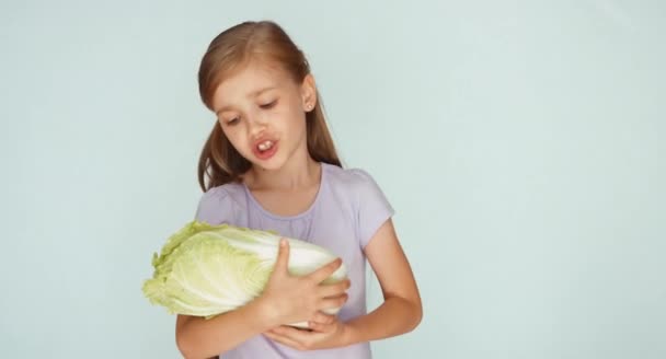 Дівчина грає з капустою і співає колискову. Дитяча кусає капусту — стокове відео
