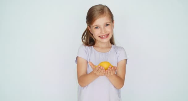 Uma rapariga a mostrar limão. Criança rindo da câmera — Vídeo de Stock