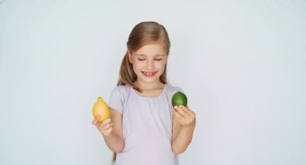 Fille considère citron et citron vert et sourire à la caméra — Video