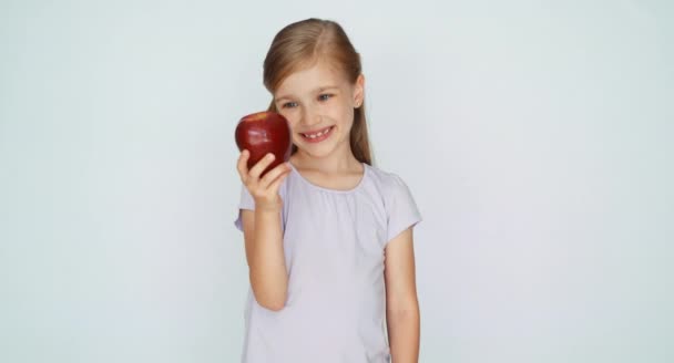 Девушка нюхает, целует яблоко и смеется. Пальцем вверх. Хорошо. — стоковое видео