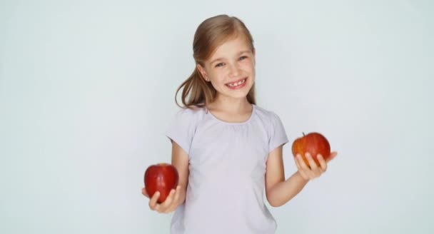 Девушка играет с двумя яблоками и улыбается — стоковое видео