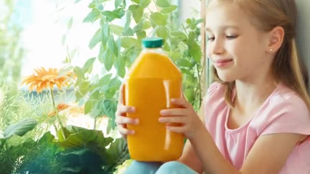 Chica sosteniendo la botella de jugo de naranja y sonriendo. Ampliación — Vídeos de Stock