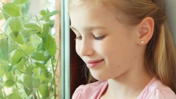 Closeup portrait girl sniffing tomato against window and offers at camera — Stock video