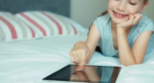 Meisje met tablet pc liegen en glimlachend op camera — Stockvideo