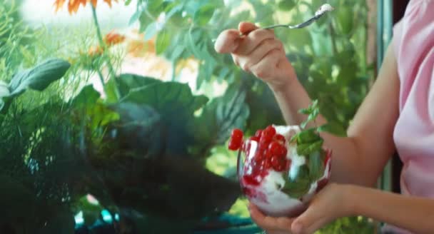 Detailní portrét dívka jíst zmrzlinu a usmívá se na kameru. Dítě sedí na okenním parapetu — Stock video