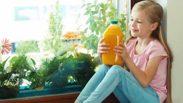 Girl holding bottle of orange juice and smiling at camera. Zooming — Stock Video