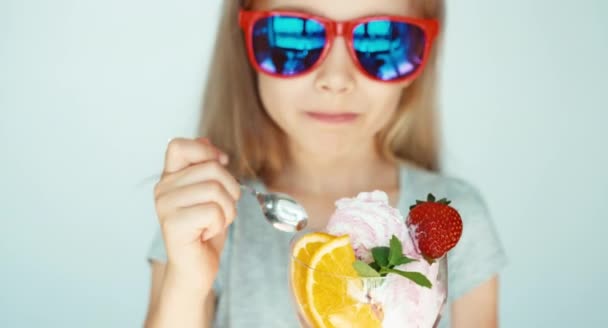 Portrait happy child in sunglasses eating ice cream and smiling at the camera on the white background. Closeup. Child nods — Stock Video